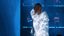 a woman wrapped in a clear plastic blanket stands in front of a blue background