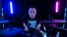 a man wearing a black shirt with the letter j on it playing drums