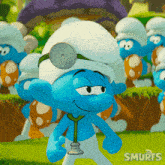 a smurf wearing a doctor 's hat and stethoscope stands in front of a group of smurfs