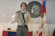 a boy scout is standing in front of a flag that says ' beast ' on it