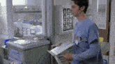 a man in a scrub top is standing in a hospital room holding a piece of paper