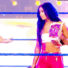 a woman in a wrestling ring holding a purple belt that says reign