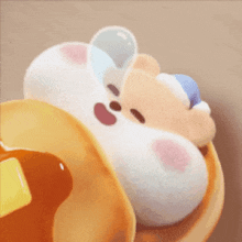 a stuffed animal is laying on top of a pancake with syrup .