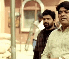 a man in a striped shirt is standing next to another man in a striped shirt .