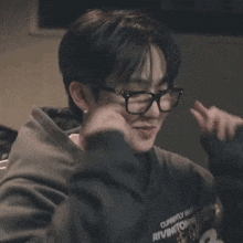 a close up of a person wearing glasses and a hoodie .
