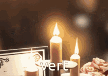 three lit candles are on a table next to a card that says vert