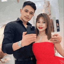 a man is taking a picture of himself and a woman in a red dress