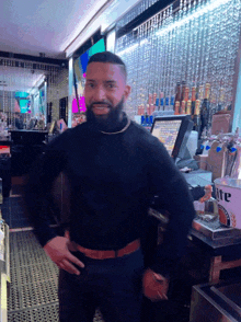 a man in a black turtleneck stands in front of a miller lite bucket