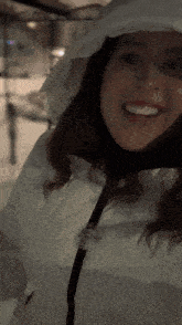a woman in a white jacket with a hood smiles