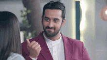 a man in a pink suit giving a thumbs up to a woman