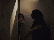 a man and woman are standing in a dark hallway