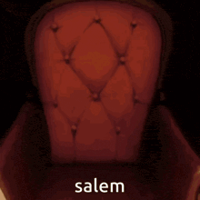 a cartoon character is sitting in a red chair with the word salem written on it .