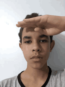 a boy with his hand on his forehead looking at the camera