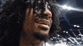 a man with dreadlocks and a beard is smiling with his mouth open
