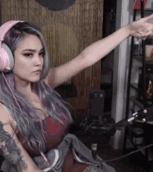 a woman wearing pink headphones is sitting in front of a microphone with her arms outstretched