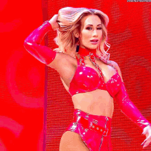 a woman in a red outfit is standing in front of a red screen .