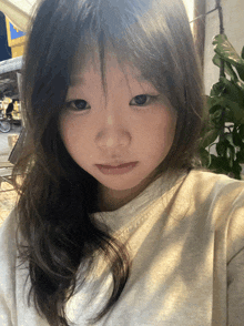 a young girl with long hair takes a selfie in front of a plant