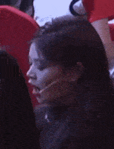 a woman wearing a microphone is sitting in a theatre .