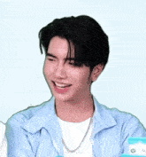 a young man wearing a blue shirt and a white t-shirt is smiling with his mouth open .