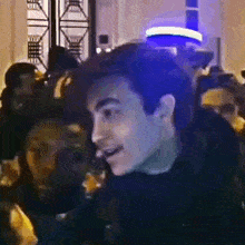 a man is standing in a crowd of people and smiling .