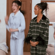 two women in plaid pajamas are dancing in a room