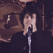 a man singing into a microphone with drums in the background