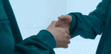 two people shaking hands with one wearing a blue sweatshirt