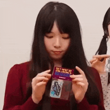 a woman with long black hair is holding a package of stickers .
