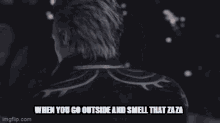 a man with gray hair and a black jacket is standing in a dark room and smelling that zaza .