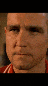 a close up of a man 's face with a red and white shirt on