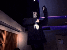 a man wearing a black shirt with a skull on it stands in a dark room