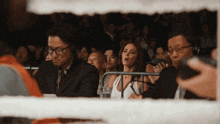 a group of people are watching a boxing match and one woman is wearing headphones