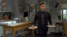 a man in a black shirt and blue tie is holding two plates of food