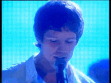 a man in a white shirt is singing into a microphone .