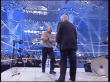 a referee talks to a wrestler in front of a sign that says wrestling