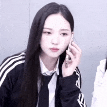 a girl with long black hair is wearing a black and white adidas jacket