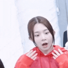 a woman in a red hoodie is making a funny face with her mouth open .