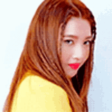 a close up of a woman 's face with long red hair and a yellow shirt .