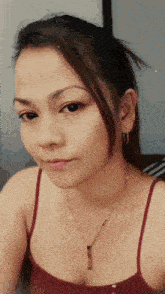 a woman is wearing a red tank top and a necklace