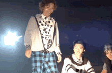 a man in a dalmatian shirt is standing next to another man in a plaid skirt