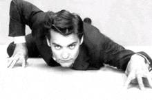 a black and white photo of a man in a suit crawling on the ground