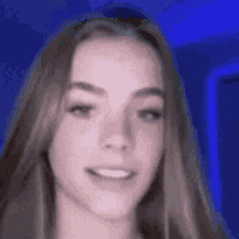 a close up of a woman 's face with a blue background and a smile on her face .