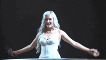 a blonde woman in a white dress stands in front of a black background