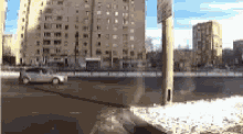 a car is driving down a snowy street in front of a building .