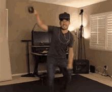 a man wearing a virtual reality headset and headphones is dancing in a living room .