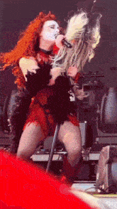 a woman with red hair is singing into a microphone while another woman looks on