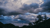 a cloudy sky with mountains in the background