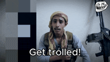 a man with a scarf around his head is holding a gun and says get trolled