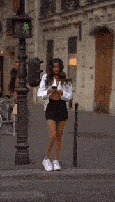 a woman wearing a white shirt and a black skirt is crossing the street