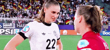 a female soccer player wearing the number 22 jersey talks to another player